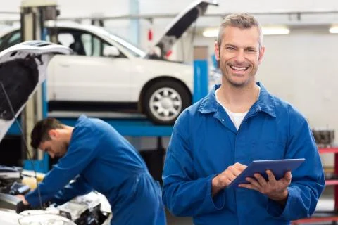 Smiling mechanic using a tablet pc 스톡 사진