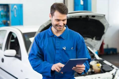 Smiling mechanic using tablet pc Stock Photos