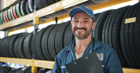 Smiling mechanic in work uniform looking camera at car tires shop service 스톡 동영상 160093435