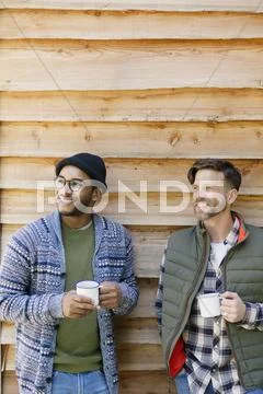 Smiling men drinking coffee outside cabin Stock Photos