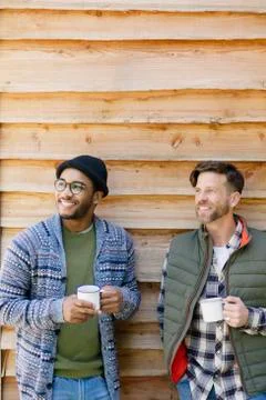 Smiling men drinking coffee outside cabin Stock Photos