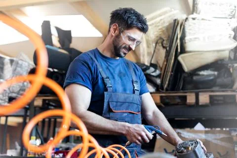 Smiling metal worker using equipment in workshop Stock Photos