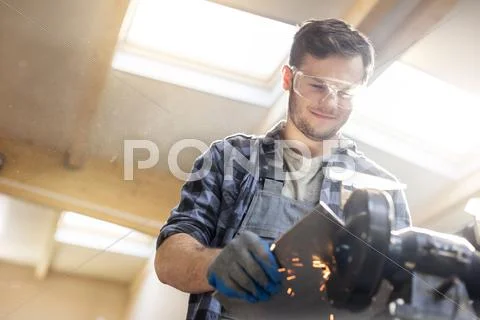 Smiling metal worker using sander in workshop Stock Photos