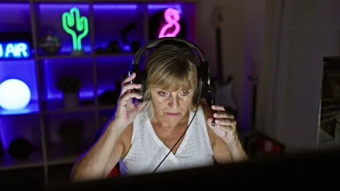 Smiling middle age blonde bombshell streaming, wired in play mode, gaming r.. Stock Footage 263469253