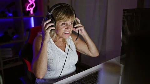 Smiling middle age blonde bombshell streaming, wired in play mode, gaming r.. Stock Footage 263469392