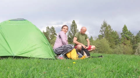Smiling middle-aged couple folding sleeping bags and wrapping up camp after a ni Video stock 308197987