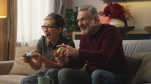 Smiling middle-aged couple play video game with gamepads, enjoying hobby Stock Footage 343607228