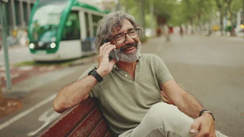 Smiling middle-aged man with gray hair and beard wearing casual clothes sits on Stock Footage 226501755