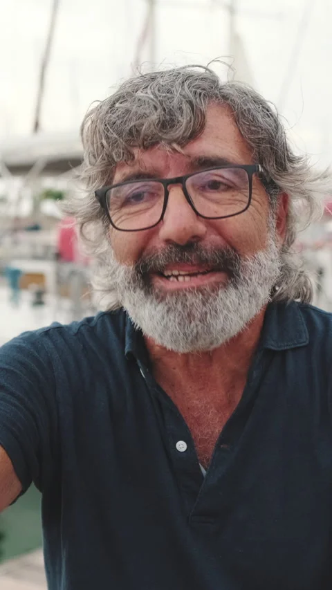 Smiling middle aged man sitting in port making video call on mobile phone Stock Footage 252207739