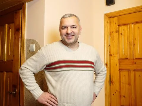 Smiling middle aged man standing indoors with hands on hips, looking at the c Stock Photos