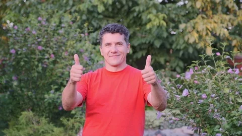 Smiling middle aged man wearing red t-shirt gesturing outdoor Stock Footage 112756393