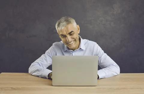 Smiling middle-aged man work on laptop typing Stock-Fotos