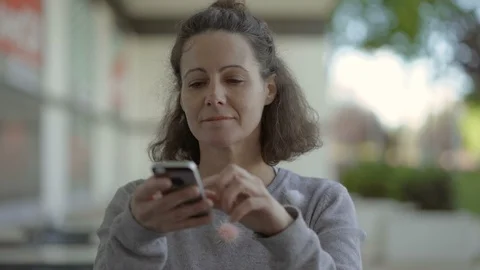 Smiling middle aged woman using smartphone on street. Video stock 108173630