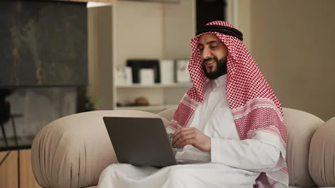 Smiling Middle Eastern businessman counting money and checking profits online Stock Footage 327484994