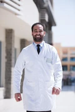 Smiling Middle Eastern eye doctor in white coat at a modern hospital clinic in Stock Photos