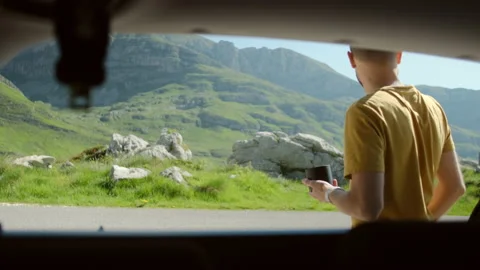Smiling millennial man opens car trunk and takes backpack gets things out. Stock Footage 146616453