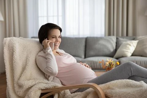 Smiling millennial pregnant female calling gynecologist get remote consultation Stock Photos