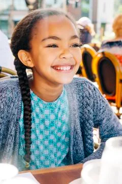 Smiling Mixed Race girl sitting at restaurant table Stock Photos