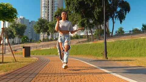 Smiling mixed race millennials stroll outdoors speaking using app on smartphone Stock Footage 114757299