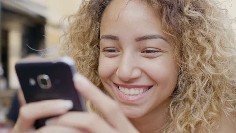 Smiling mixed race woman using smartphone outdoor Video stock 80657648