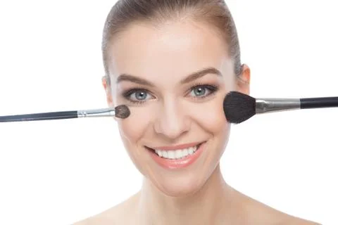 Smiling model applying make-up over white background Stock Photos