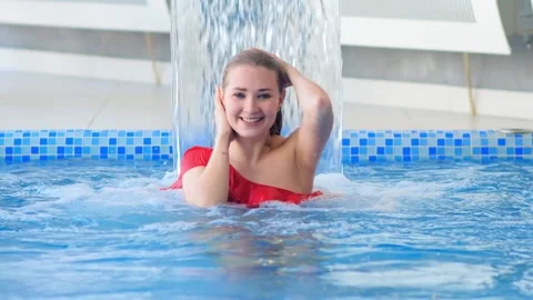 Smiling model poses in swimming pool looking to camera Video stock 133043011