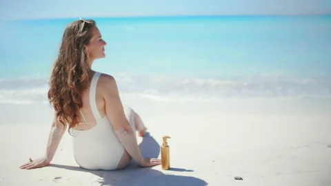Smiling modern 40 years old woman sitting at beach Stock Footage 224196357