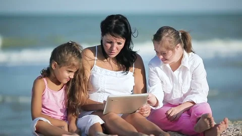 Smiling mother and daughters using tablet on the beach Video stock 80886012