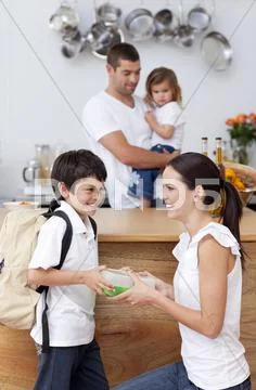 Smiling mother giving school lunch to her son Stock Photos