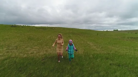 Smiling mother in green dress and daughter are running together Stock Footage