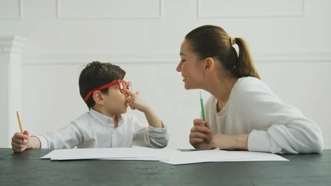 Smiling mother talking to her son while doing homework at home 스톡 동영상 106315600