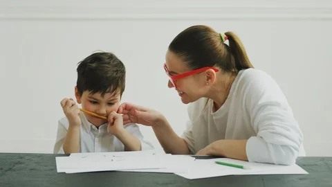 Smiling mother talking to her son while doing homework at home Stock Footage 106316049