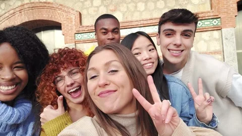Smiling multi-ethnic friends gesturing while taking a selfie outdoors Video stock 259637085