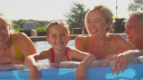 Smiling Multi-Generation Family On Summer Holiday Relaxing In Swimming Pool On Vidéo 210588632
