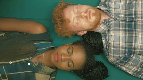 Smiling multi-race couple with closed eyes are lying parallel to each other on Video stock 74188253