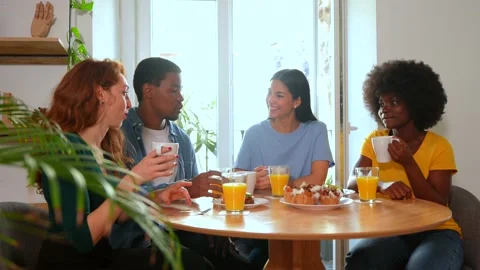 Smiling multiethnic friends over breakfast with orange juice and muffins at.. Stock Footage 235906325