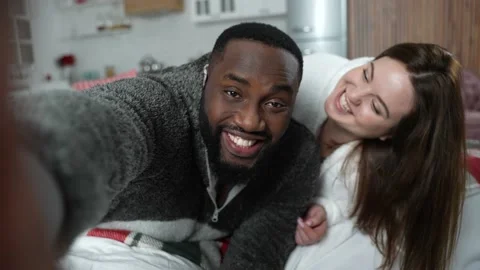 Smiling multinational couple taking selfie at home Stock Footage 148683744