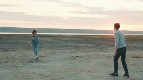 Smiling multinational couple throwing frisbee to each other Stock Footage 162065521