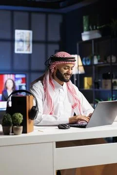 Smiling Muslim guy using digital laptop Stock Photos