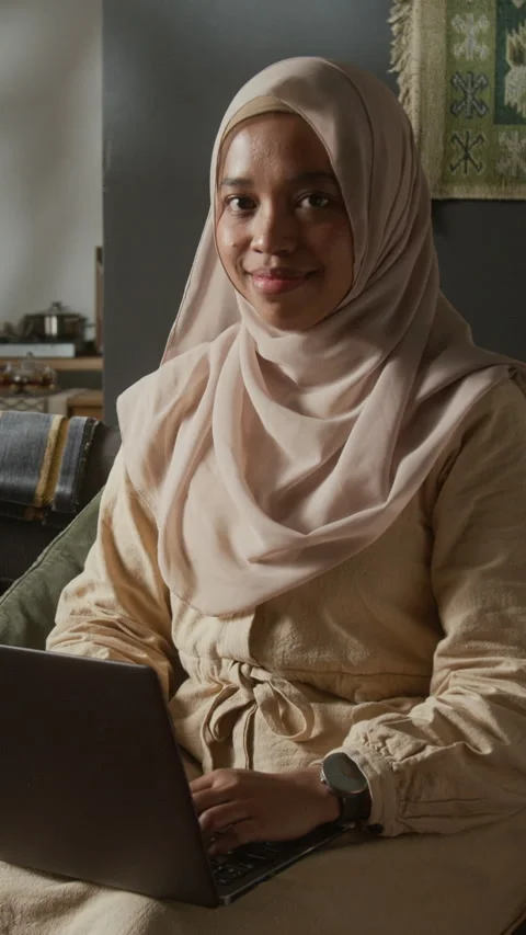Smiling Muslim Woman Using Computer and Looking at Camera at Home Vertical Stock Footage 331816650
