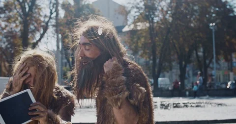 Smiling neanderthals in animal fur using modern tablet browsing internet having Stock Footage 118396574