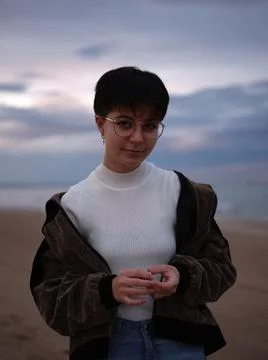 Smiling non-binary girl standing looking at the camera with the beach behind her Stock-Fotos