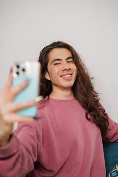 Smiling non-binary person having fun while taking a selfie with a mobile phon Stock Photos