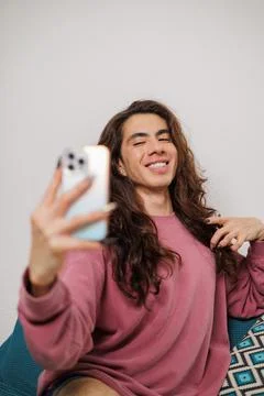 Smiling non-binary person having fun while taking a selfie with a mobile phon Stock Photos