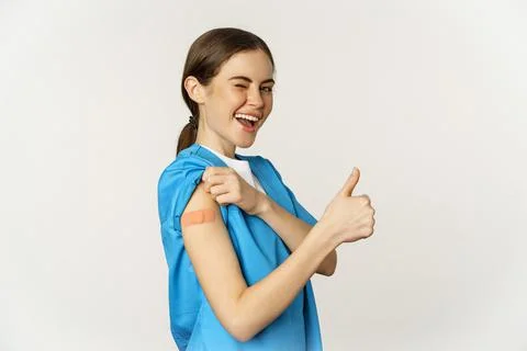 Smiling nurse, doctor in scrubs, medical worker showing her vaccinated shoulder Stock Photos