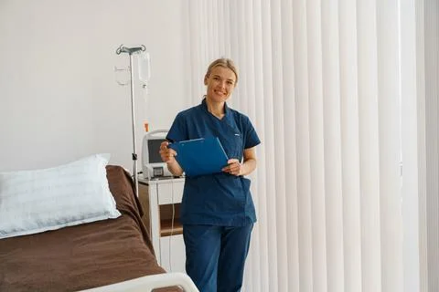 Smiling nurse holding tablet while stands in hospital ward ready to work Stock Photos