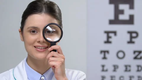 Smiling nurse looking at camera through magnifying glass, health check, vision Stock Footage 110692817