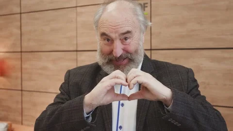 Smiling old bearded man showing hands sign heart shape looking at camera. Stock Footage 148951255