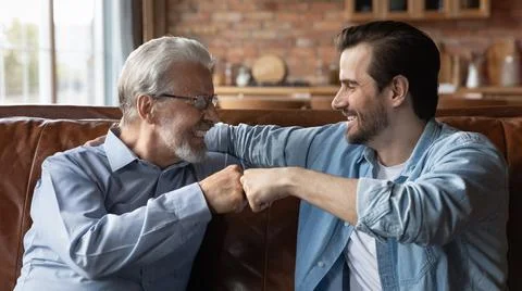 Smiling old father and adult son give fist bump Stock Photos