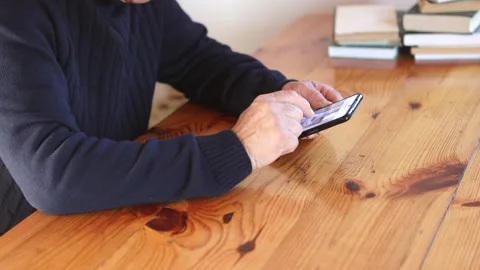 Smiling old man using smartphone while sitting on couch. Stock Footage 165173872
